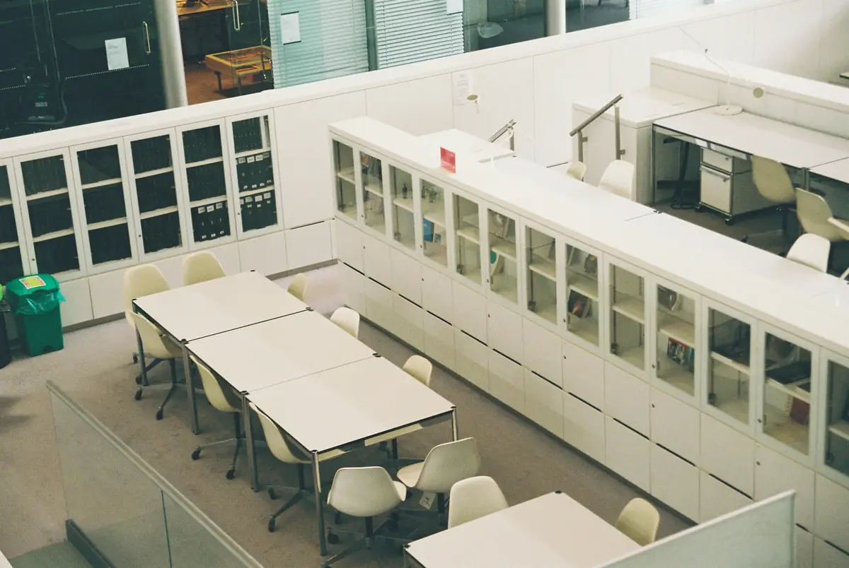 A quiet university reading room with glass-fronted archive cabinets and study tables